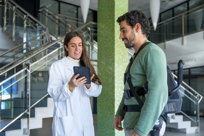 Impresión enmarcada : Exoesqueleto mecánico, fisioterapeuta doctora femenina hablando con tableta con persona discapacitada con esqueleto robótico.