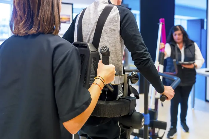 Impresión enmarcada : Exoesqueleto mecánico. Asistente de fisioterapia femenina médica ayudando a una persona discapacitada con un esqueleto robótico para caminar.