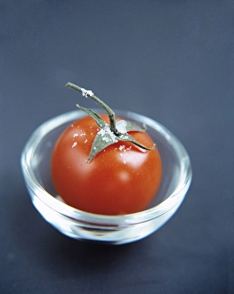 Impresiones de El tomate (Lycopersicon esculentum) en un tazón de vidrio. Este fruto tiene muchas usos en la cocina y es una buena fuente de vitaminas A y C Imágenes de agosto de 2004: Tomato