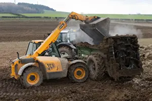 Imágenes fechadas en 2012: Cran JCB Telehendrer carga lodo en distribuidor de lodo para esparcirlo sobre campo arable en Inglaterra