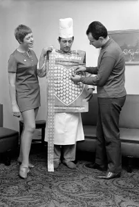 00031 Imprime: El humor. Un hombre y una mujer cubriendo a un hombre con uniforme de chef en corazones de plástico