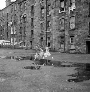 Reino Unido Imprime: Tres jóvenes amigos saltan sobre una charca fuera de un bloque de viviendas en Govan en Glasgow