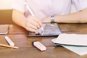 Estudiante de escuela utilizando dispositivo de computadora portátil táctil para aprender y escribir tareas del hogar, tecnología moderna para la educación.