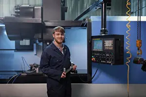 Impresiones de Aprendiz sosteniendo una banda de u-bolto frente a una máquina CNC Noviembre Imprime: Aprendiz sosteniendo una banda de u-bolto frente a una máquina CNC.