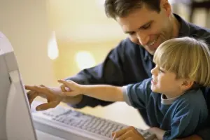2002 Imprime: Perfil lateral de un padre y su hijo utilizando una computadora.