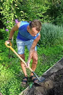 Young Gardener Imprime: A young man digging a flower bed on the plot A young man digging a flower bed on the plot