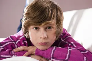 Child Looking Into The Camera Imprime: Boy lying on a couch with a contemplative expression