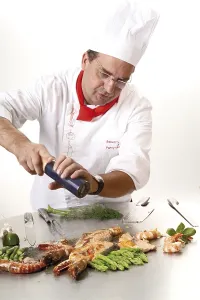 Langostino Imprime: El chef agregando pimienta en una sartén de teppan.