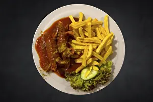 Meat Products Nutrition Imprime: Currywurst with chips on a dark background