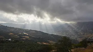 Greek Island Landscapes Imprime: Dramatic landscape with sun rays breaking through a cloud cover