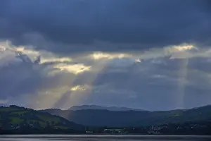 Scottish Lake Photography Imprime: Dramatic rays of light through a cloudy landscape over a lake