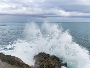 Panoramic Ocean View Imprime: A dramatic scene as powerful waves collide with rugged rocks under a brooding sky