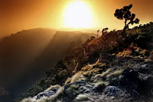 Atmospheric Landscapes Imprime: Dramatic sunset over a mountain landscape with tree