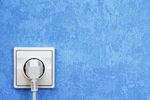 Power Supply Socket Imprime: Electrical plug connected into the socket on blue wall