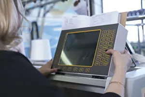 Modern Industrial Architecture Imprime: Female operator setting programme at knitting machine control panel view