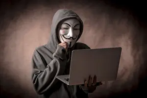 Data Security Protection Imprime: Hacker with anonymous mask with a laptop thinking about programming