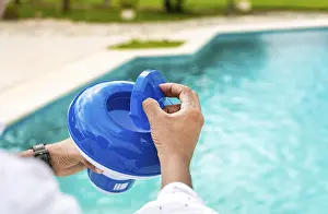 Swimming Pool Disinfection Imprime: Hands of a worker installing a pool chlorine float