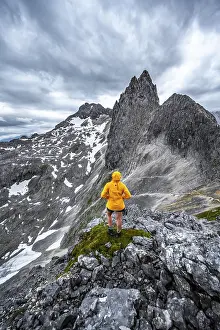 Dramatic Clouds Europe Imprime: Hiker looking at mountains under dramatic clouds