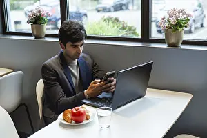 Remote Work Lifestyle Imprime: A indian man multitasks efficiently using a smartphone