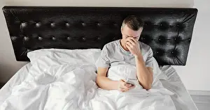 Dark Bedroom Scene Imprime: Man bed using mobile
