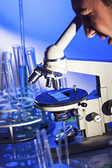 Laboratory Equipment Usage Imprime: Man is looking into the ocular of microscope
