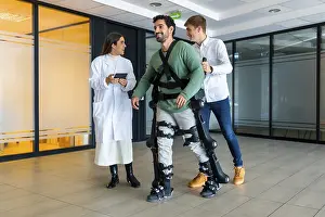 Young Adults With Disability Imprime: Mechanical exoskeleton, female doctor with device walking with disabled person with robotic skeleton in rehabilitation