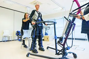 Mechanical Exoskeleton Imprime: Mechanical exoskeleton. Female physiotherapy medical assistant lifting disabled person with robotic skeleton