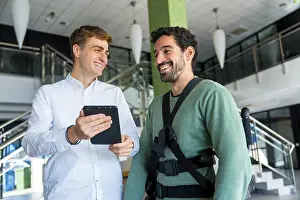 Physical Therapy Treatment Imprime: Mechanical exoskeleton, physiotherapist looking at consultation with tablet with disabled person with robotic skeleton