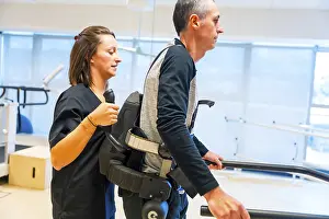 Physical Disability Support Imprime: Mechanical exoskeleton. Female physiotherapy medical assistant helping disabled person with robotic skeleton to walk