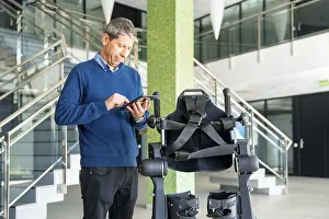 Mechanical Exoskeleton Imprime: Mechanical exoskeleton computer engineer looking at the robot with a tablet