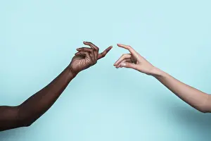 Multiethnic Unity Imprime: Two multiethnic hands reach toward each other against a solid blue backdrop