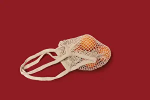 Single Colored Background Photo Imprime: Oranges in a string bag on ruby red background