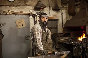 Blacksmith At Work Imprime: The portrait of bearded blacksmith preparing to work in his workshop