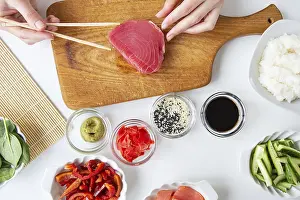 Impresiones de El proceso de preparar sushi, preparar todos los ingredientes para el sushi, la chica está sosteniendo atún con palillos Atún Imprime: El proceso de preparar sushi.
