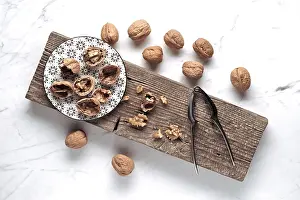 Wooden Board Arrangement Imprime: A rustic setup features whole and cracked walnuts on a patterned plate