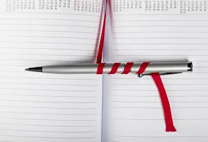 Office Supply Desk Utensils Imprime: Silver pen on opened notebook with red string