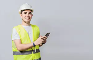 Young Engineer Imprime: Smiling engineer using cell phone looking at camera