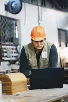 Woodworking Profession Imprime: Successful worker using a computer in the carpentry workshop