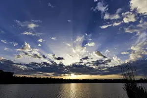 Urban Evening Atmosphere Imprime: Sunset piercing the clouds from over the ocean