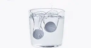 Full Body Length Tablet Drop Imprime: Tablets Falling and Dissolving into a Glass of Water against White Background