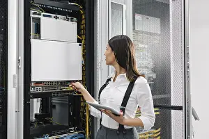 Digital Data Collection Imprime: Technician using tablet pc while analysing server in large data center