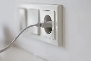 Power Supply Concept Imprime: White power plug in a socket on the wall
