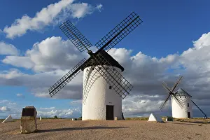 Dramatic Cloudy Skies Spain Imprime: Windmill in a rural setting under a blue sky with dramatic clouds